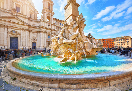 Rome, Italy. Fountain of the Four Rivers on Piazza Navona. Ancient fountain, statues, obelisk design of Bernini. Famous landmark touristic location near Sant Agnese in Agone church. Sunny summery day. photo