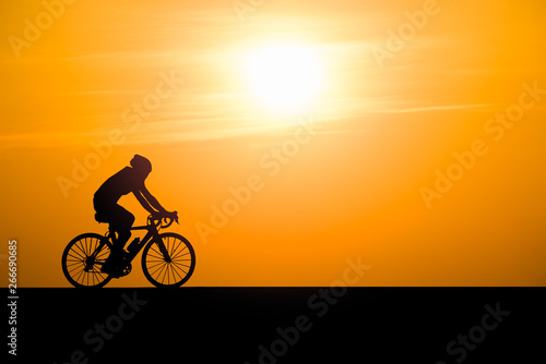 Silhouette man cycling on sunset background