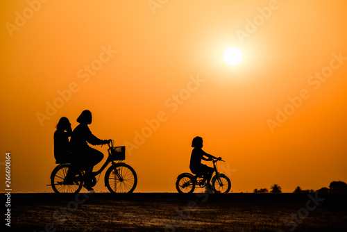 Silhouette girl cycling on sunset background