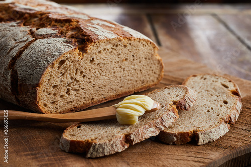 Loaf of sliced rye bread with butter spreader