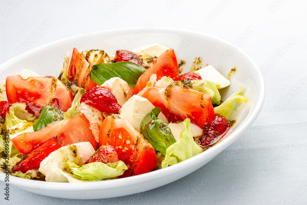 Caprese salad with strawberries. Salad with mozzarella, tomatoes, Basil and strawberries. On white background Caprese salad with strawberries. Salad with mozzarella, tomatoes, Basil and strawberries. On white background