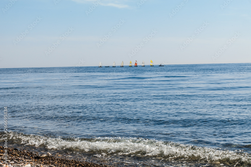 sailboats on the horizon are sailing on the blue sea