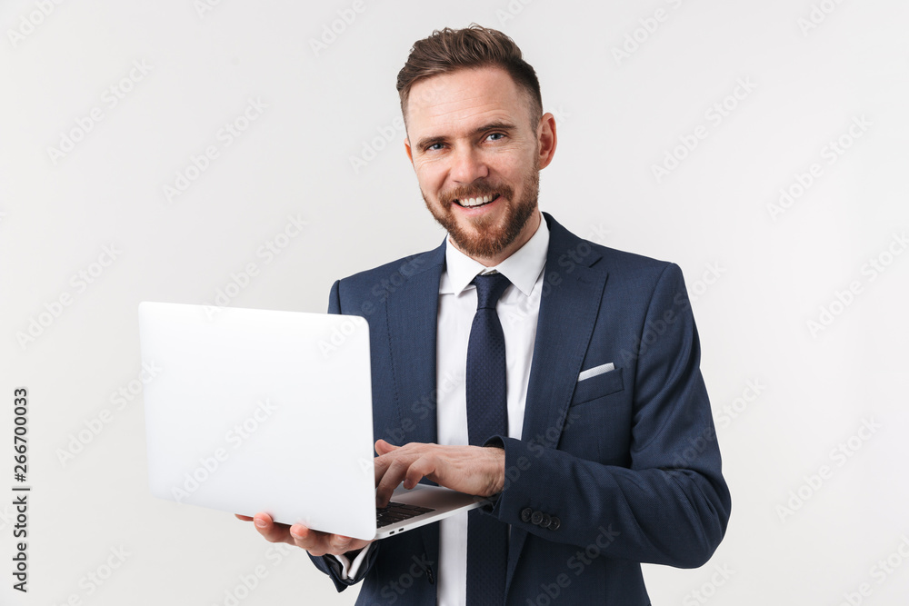 Excited businessman posing isolated over white wall background holding laptop computer. Excited businessman posing isolated over white wall background holding laptop computer.