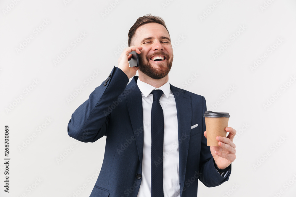 Happy businessman posing isolated over white wall background drinking coffee talking by phone. Happy businessman posing isolated over white wall background drinking coffee talking by phone.