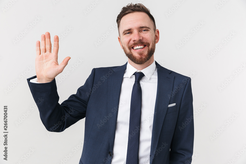 Happy young businessman posing isolated over white wall background waving. Happy young businessman posing isolated over white wall background waving.
