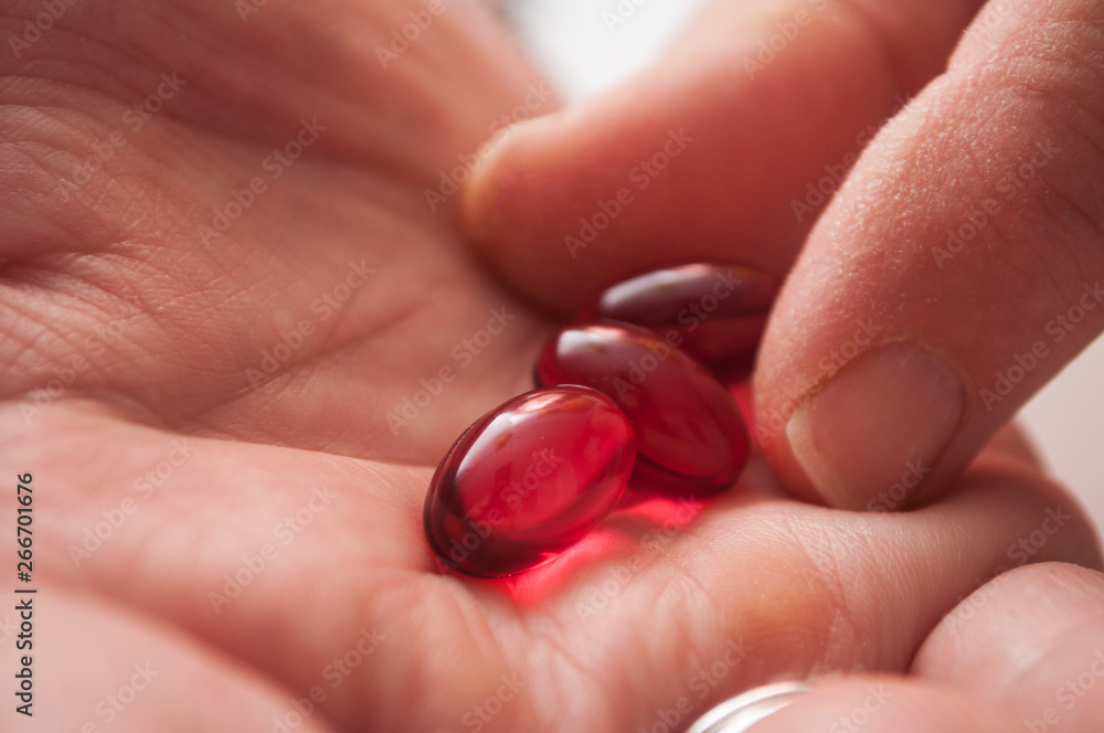 closeup of red pills in hand on white background closeup of red pills in hand on white background