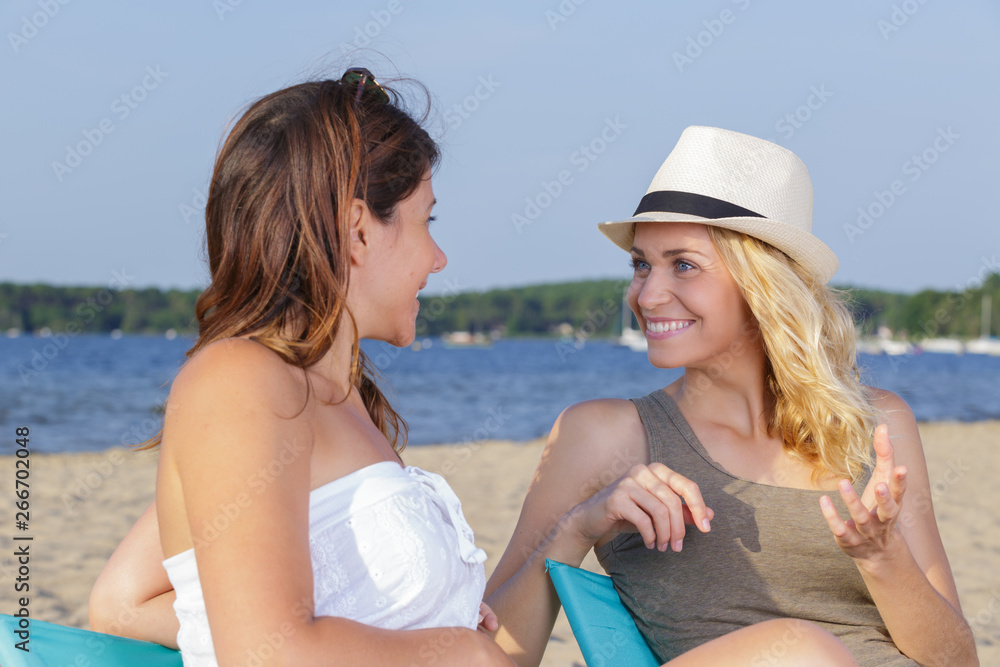 two pretty girls sitting on beach talking two pretty girls sitting on beach talking