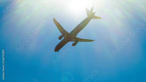 Commercial passenger airplane flying overhead against blue sky. Fast Travel and transportation concept Copy space