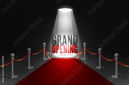 Grand opening event banner in spotlights. Red carpet between two barriers. Red ribbon cut ceremony.