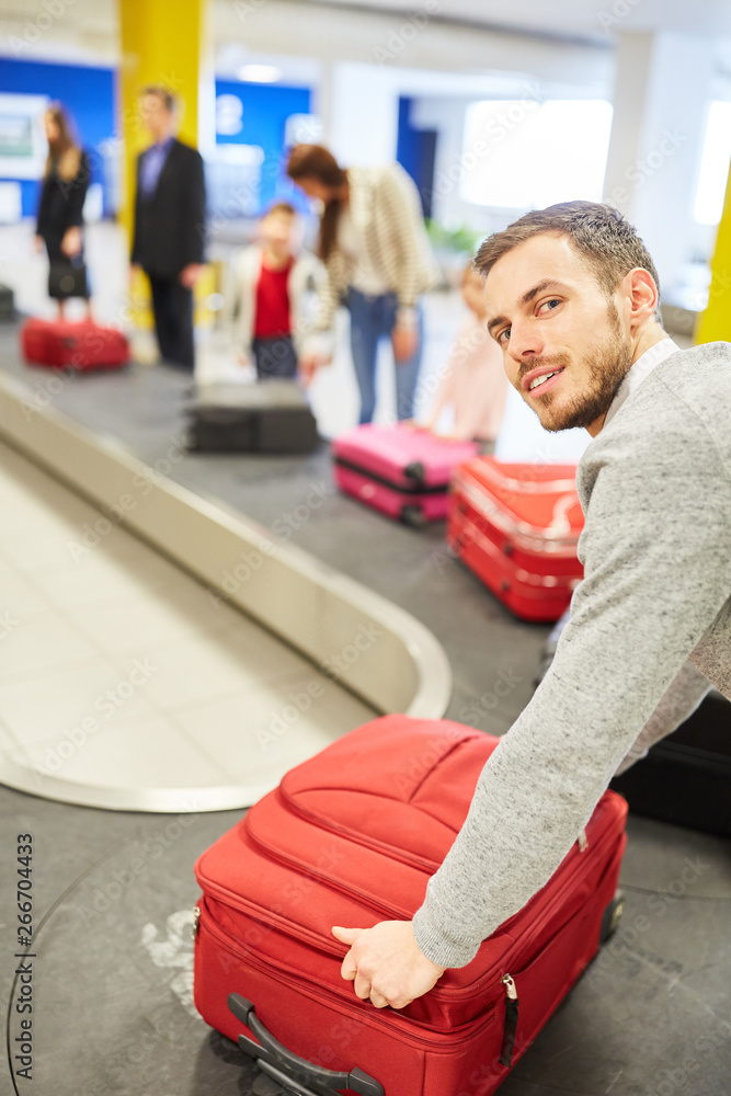 Mann als Passagier am Gepäckband holt Koffer ab Stock Photo | Adobe Stock