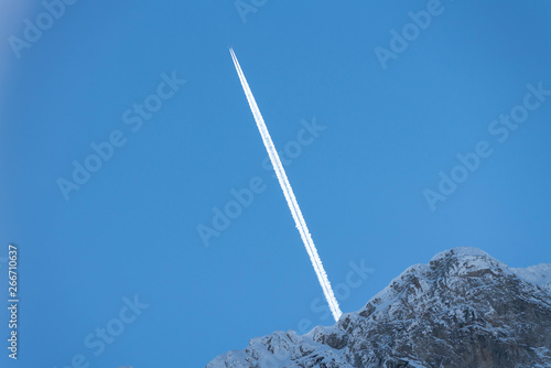 Kondensstreifen eines Flugzeugs im Gebirge