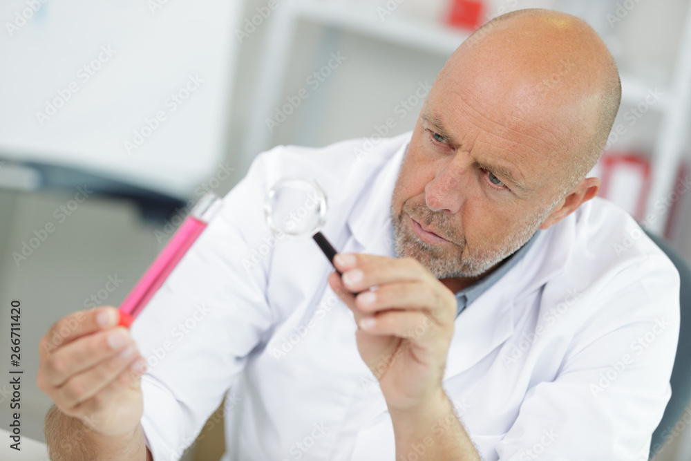 scientist holding magnifying glass at laboratory scientist holding magnifying glass at laboratory