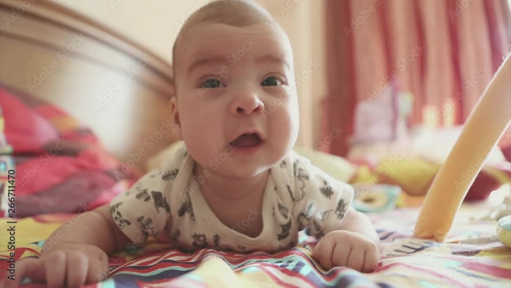a newborn baby lies on his stomach and learns to hold his head. The kid looks at the camera a newborn baby lies on his stomach and learns to hold his head. The kid looks at the camera
