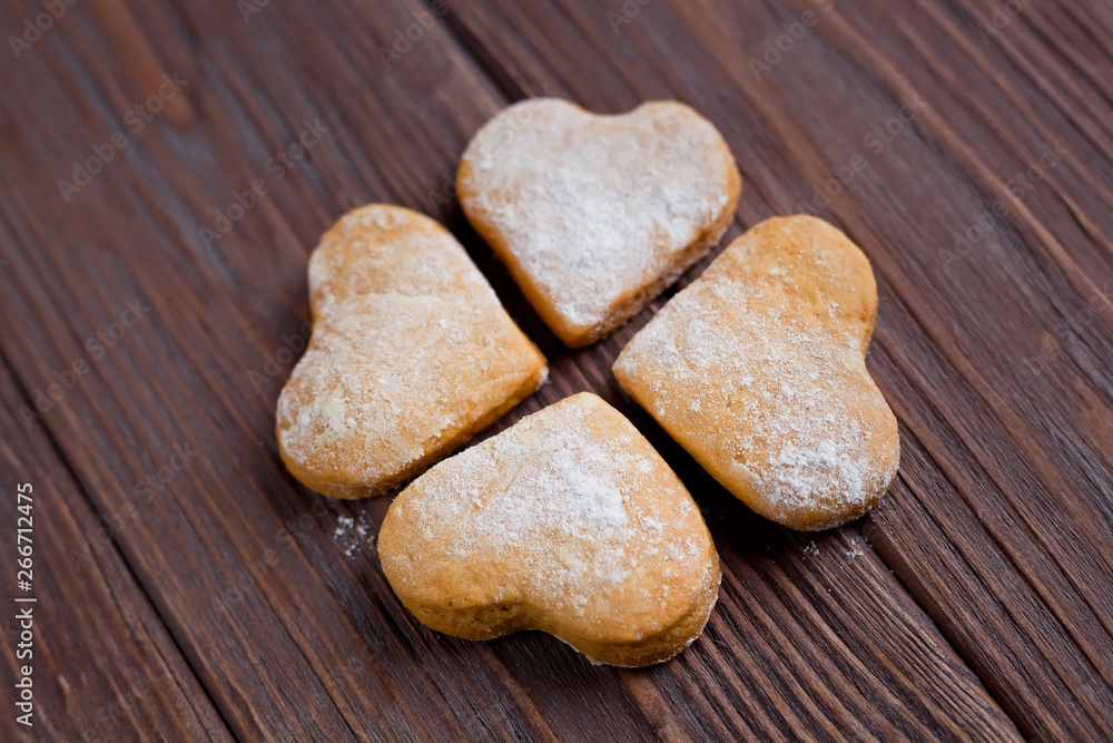 four heart shaped cookies, luck symbol clover on a brown wooden background four heart shaped cookies, luck symbol clover on a brown wooden background