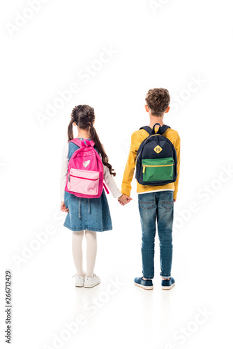 back view of schoolchildren with backpacks holding hands isolated on white