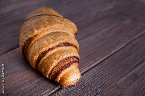Fresh croissant on a brown wooden table. Side view.