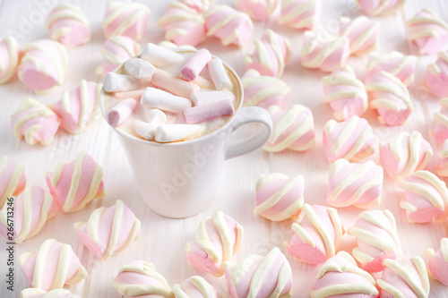 cappuccino or cocoa with marshmallow in a white cup on the background of marshmallow on a white table in bulk