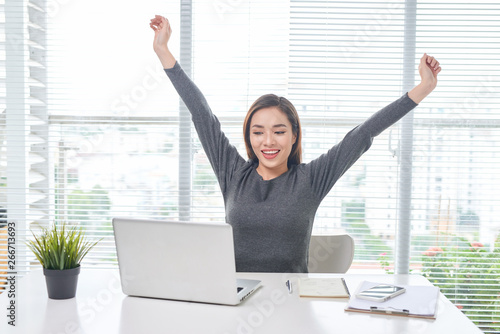 Young business woman working at home behind a laptop and stretching her hands. Creative Scandinavian style workspace