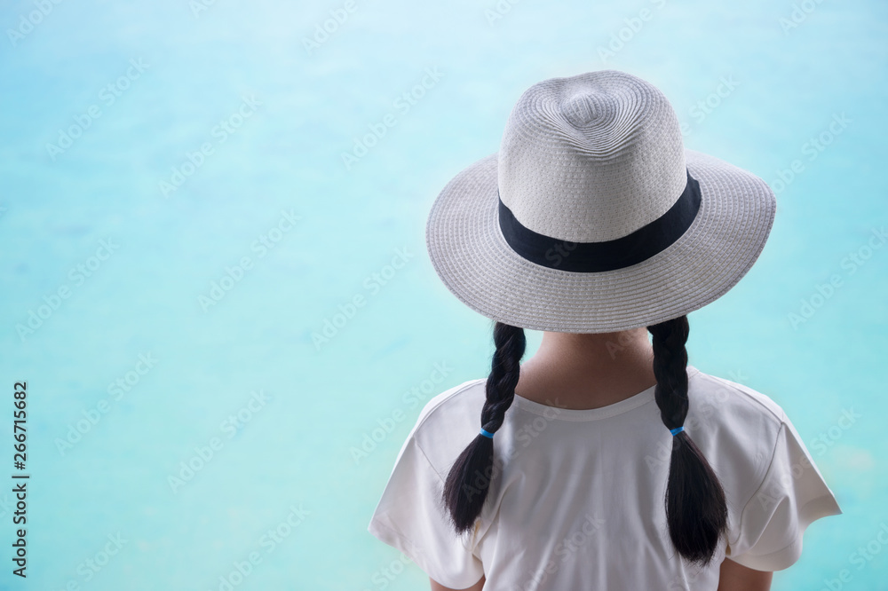back of pigtails hair girl kid with summer hat with blue sea water background