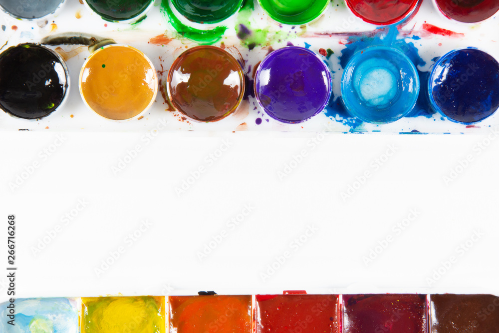 A set of children's paints in round, rectangular forms close-up. Copy space for text In frame