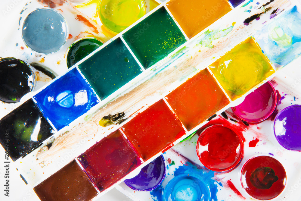 A set of children's paints in round, rectangular forms close-up. Original creative background