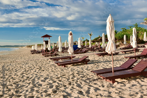 Obraz na płótnie Sun loungers and umbrellas on an empty sandy beach. Summer sunny cloudy blue sky. Kamran. Vietnam. w salonie
