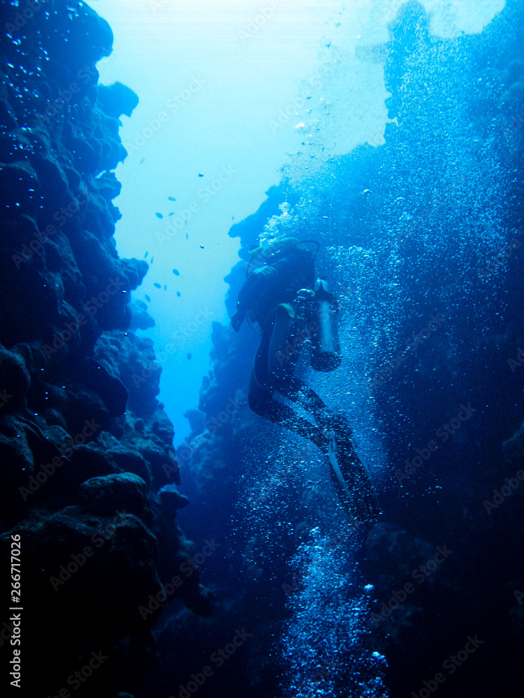 Silhouette of a diver swimming out of an underwater canyon in Dahab, Egypt
