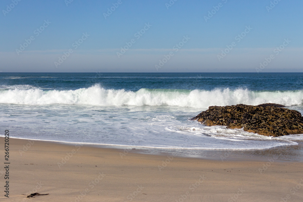 Waves crashing on rocks on Atlantic Ocean beach. Scenic seascape. Beautiful surf at seaside. Splashing waves with foam. Travel and vacation on shore. Rocky coastline. Nature power.