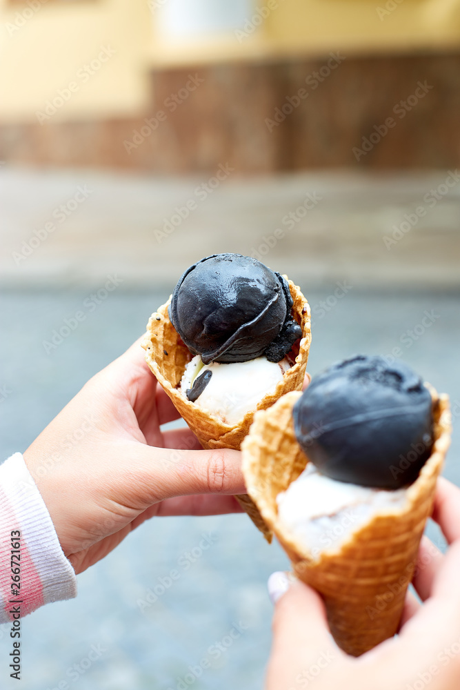 Female in hand charcoal and vanila ice cream Female in hand charcoal and vanila ice cream