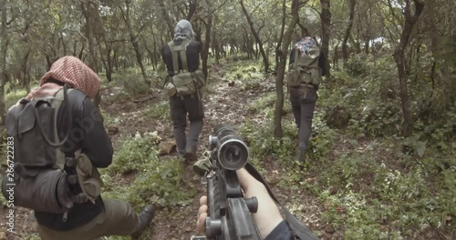 POV footage of armed terrorists patrolling a forest area photo