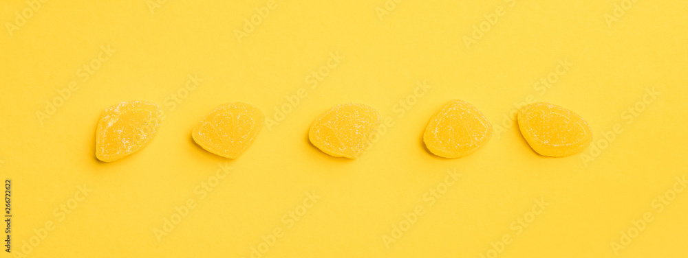 panoramic shot of delicious sugary jellies in row on yellow background