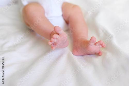 Feet newborn boy 1 month lying on his white bed. Medicine, breastfeeding at birth, regime of the day and sleep of the child.
