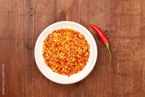 Red hot cayenne pepper, crushed and fresh chili, shot from the top on a dark rustic wooden background with a place for text