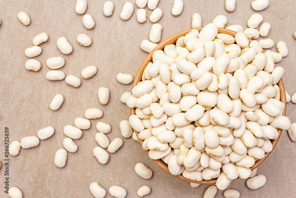 Dry lima beans in ceramic bowl on stone background, top view, wallpaper, close up.