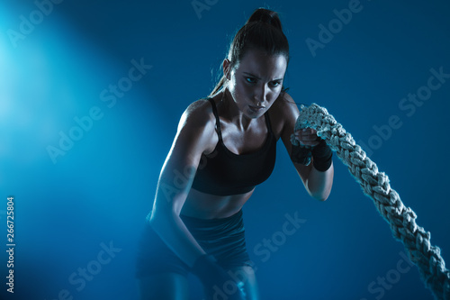 Sportswoman exercising with battling ropes photo