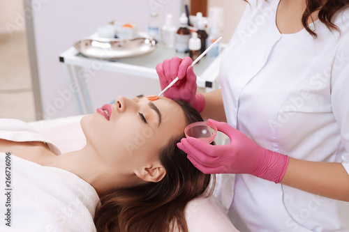 Young woman cleaning face skin in salon.