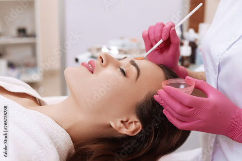 Young woman cleaning face skin in salon.