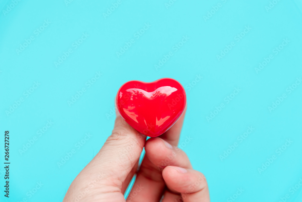 Fototapeta premium One hand holding red heart shaped ceramic for love concept.