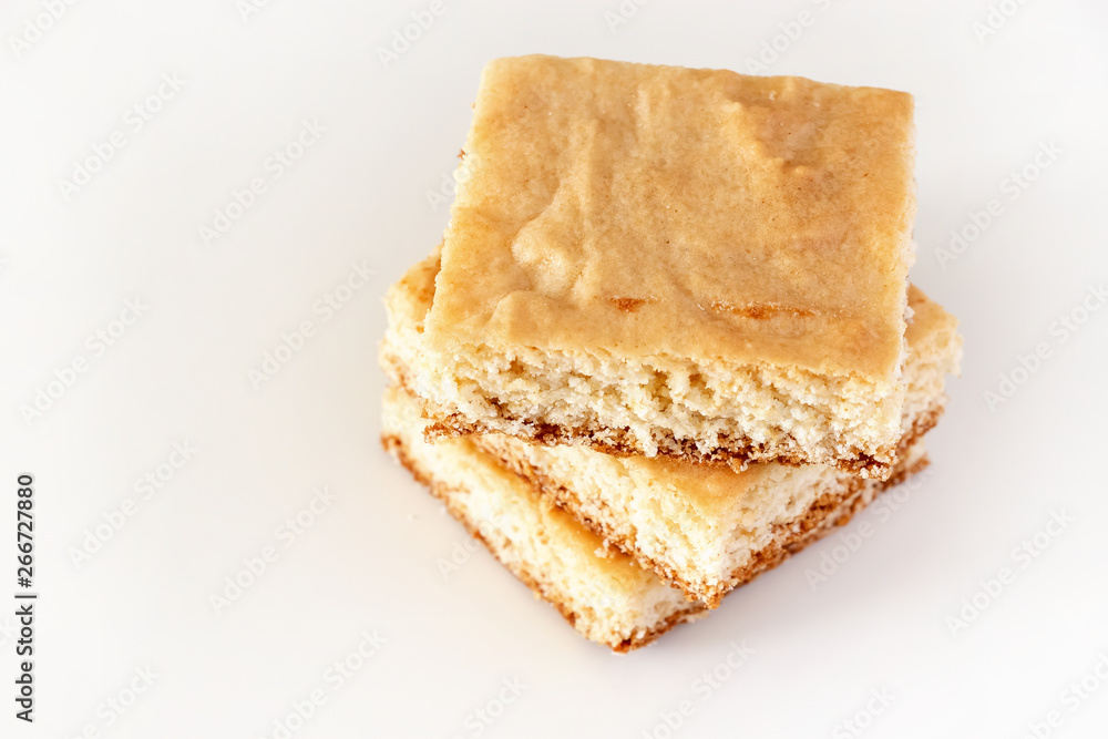 Stack of square pieces lemon shortbread cake isolated white background. Selective focus. Stack of square pieces lemon shortbread cake isolated white background. Selective focus.