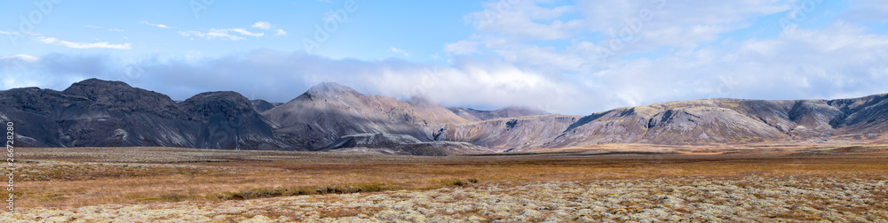 Landscape panoramic panorama view of Laugarvatn mountains with clouds covering on golden circle in Iceland during day and blue color sky in autumn