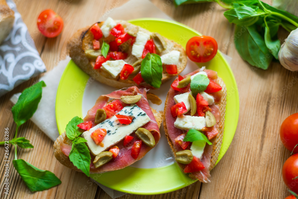 Traditional Italian bruschetta with blue cheese, feta, tomatoes, basil leaves, jamon on a wooden background. Traditional Italian bruschetta with blue cheese, feta, tomatoes, basil leaves, jamon on a wooden background.