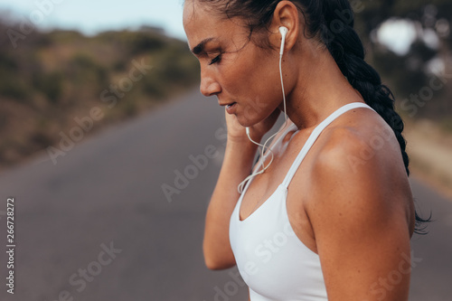 Fototapeta Naklejka Na Ścianę i Meble -  Sportswoman listening to music while jogging