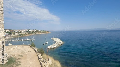 Aerial view of a medieval tower on the beach of Nea Fokea and a small boat in the harbor,Halkidiki Greece, move forward and up by drone photo