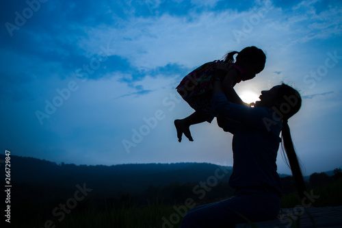 Happy Mother and her child play outdoors having fun, mother lifting daughter in rice field.