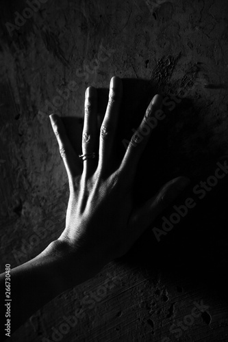 Black and white image of a womans hand pushing against a wall