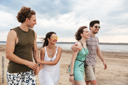 Group of a cheerful young friends walking at the beach