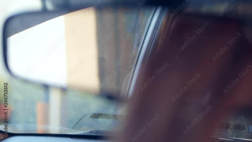 Reflection of a woman's face in the rearview mirror, a woman prepares a rear-view mirror before driving Reflection of a woman's face in the rearview mirror, a woman prepares a rear-view mirror before driving