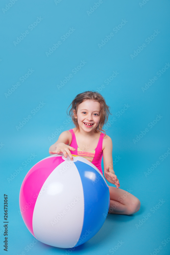 Little smiling girl with big inflatable ball on blue background Little smiling girl with big inflatable ball on blue background