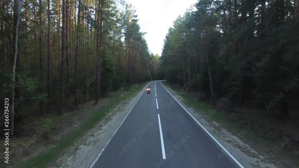 Aerial view of a biker riding a forest road, shot drone Aerial view of a biker riding a forest road, shot drone