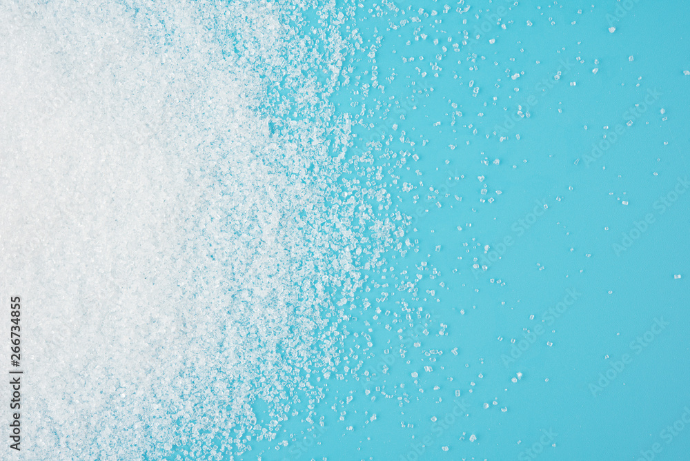 White sugar splash on blue background texture top view White sugar splash on blue background texture top view